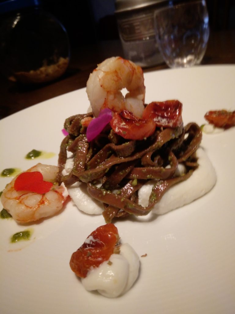 Tagliatelle al cacao con pesto, gamberi, pomodorini confit su crema di ricotta