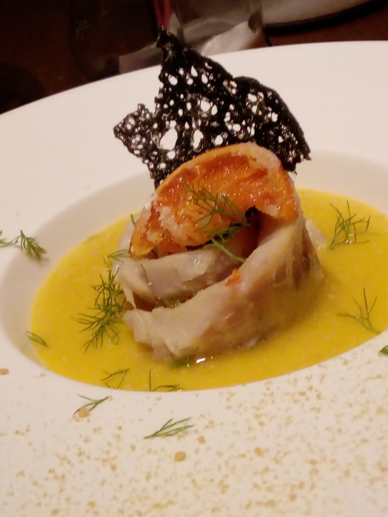 Rosa di branzino su crema di finocchi al sentore di zafferano, arancia confit e cialda al nero di seppia